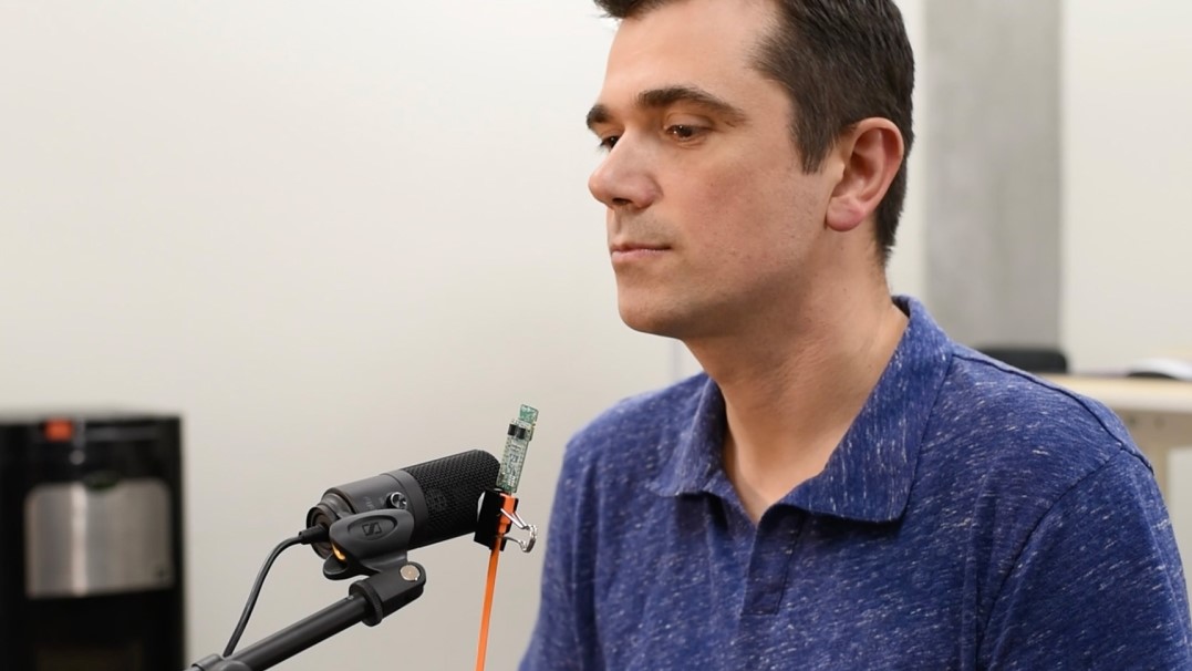 Photo of a man with microphone in front of him. 