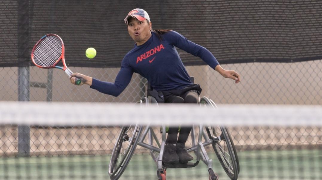 Photo of athlete in wheelchair hitting a tennis ball 