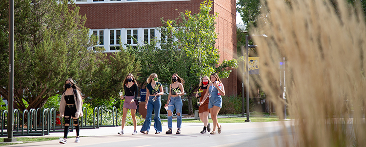Students walking outside on NAU's campus with facemasks on. 