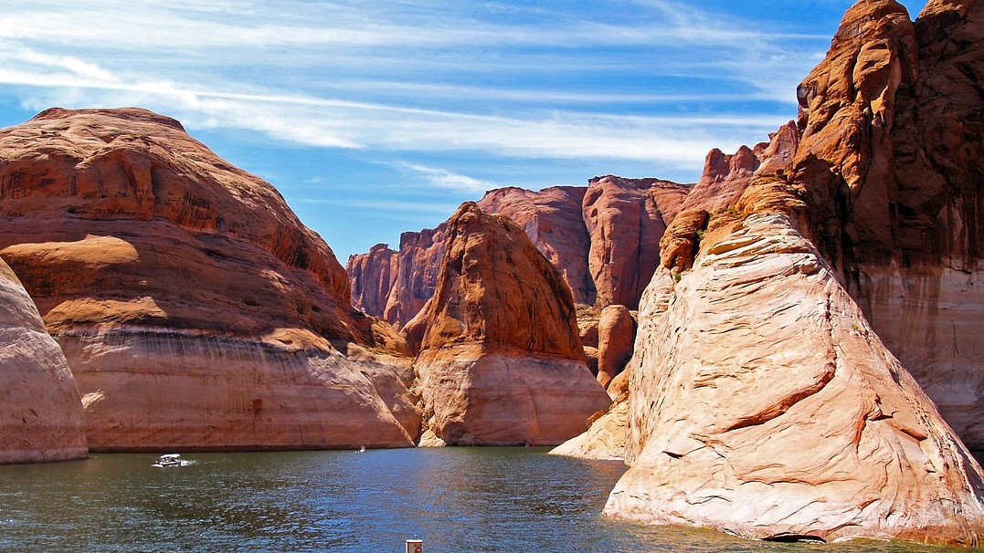 Photo of a lake with soaring red rocks jutting from the water. 