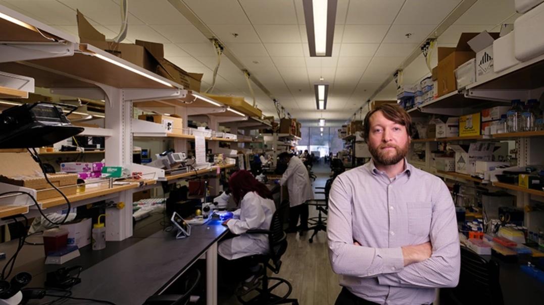 Philipp Gutruf, associate department head of biomedical engineering, is pictured in his lab with two other researchers working in the background. He is the senior author of a study that introduces a soft mesh sleeve worn around the lower thigh that monitors and analyzes leg acceleration, symmetry and step variability. 