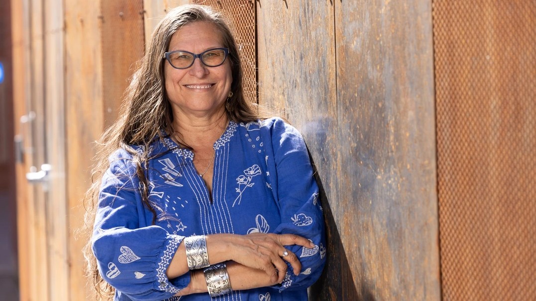 Image of Elaine Romero, a professor in the University of Arizona School of Theatre, Film and Television, in front of a wooden fence 