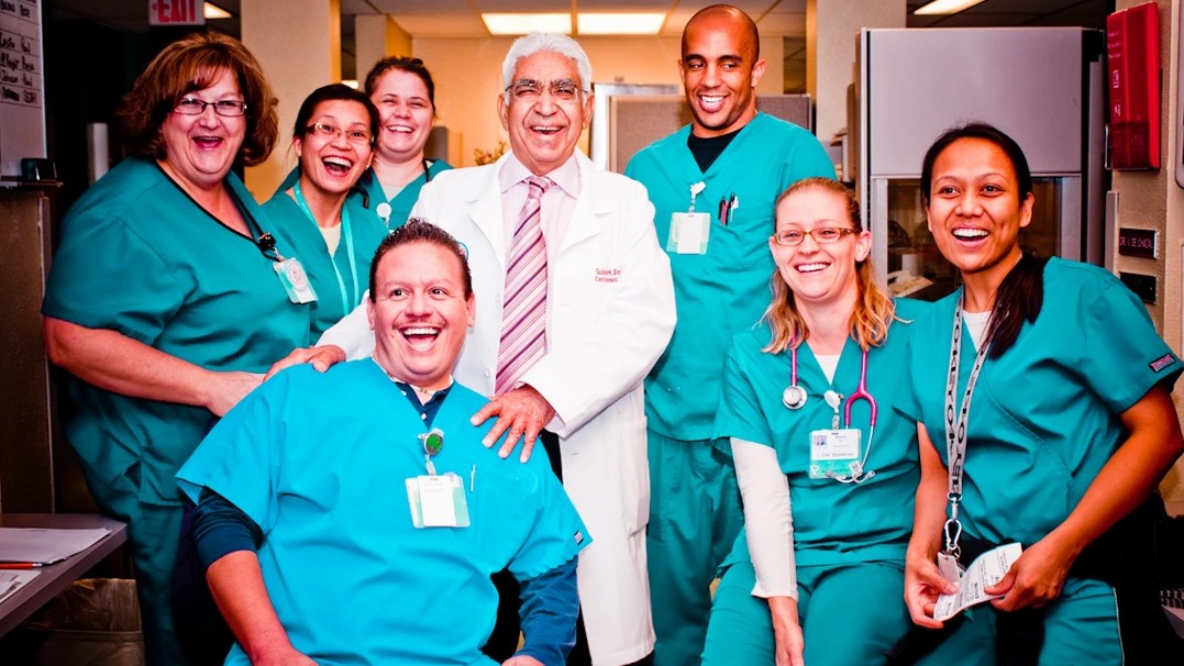Dr. Gulshan Sethi (center) is pictured with his cardiothoracic surgery team in surgical scrubs. 