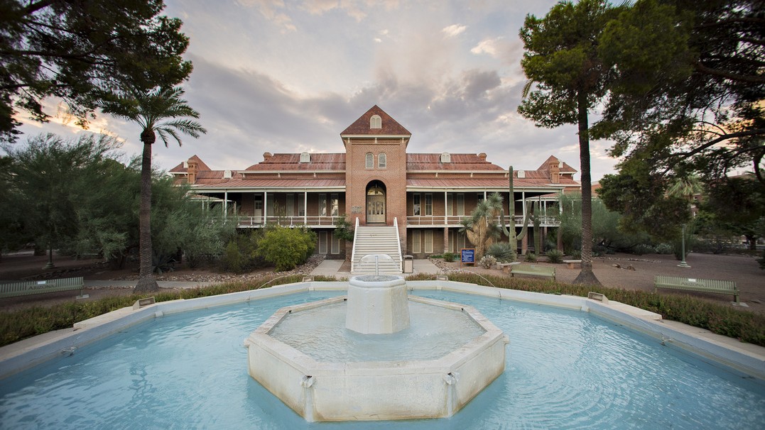 Photo of Old Main with a fountain in the foreground and clouds in the sky 