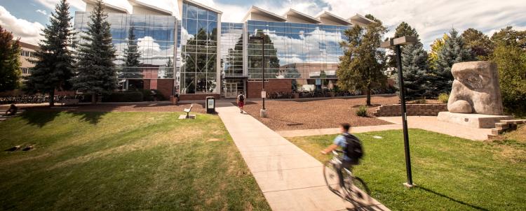 NAU student riding his bike up to a building on campus 