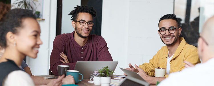 Photo of two men and a woman sitting at a table with laptops 