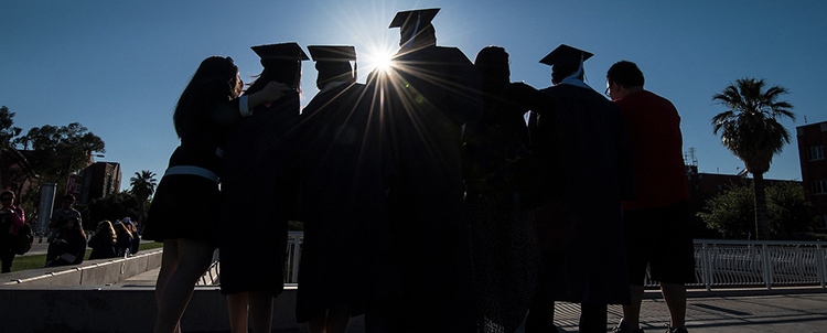 photo of college graduates in caps and gowns in silhouette 