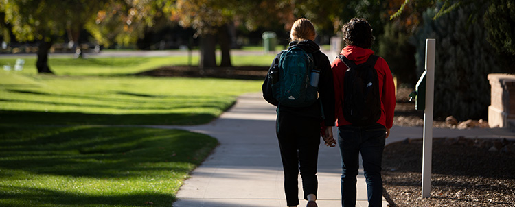 Two students walking on campus with their backs turned to the camera