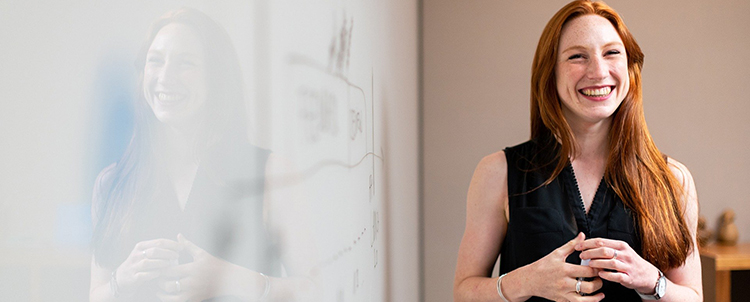 Photo of smiling woman in front of white board 