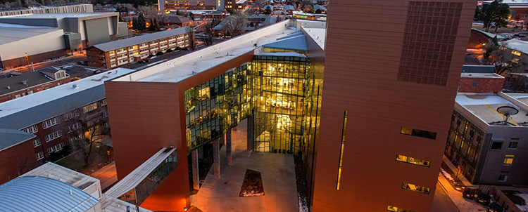 Photo of the outside of the Science Building on the NAU campus at twilight with lights on in the building 