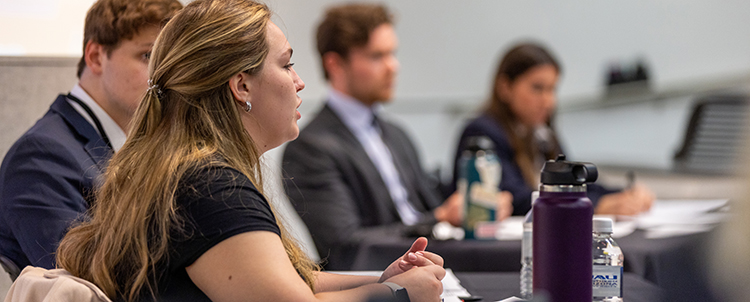 Image of four seated students participating in the Regents' Cup with a female student speaking. 