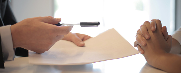 man handing pen to another holding contract