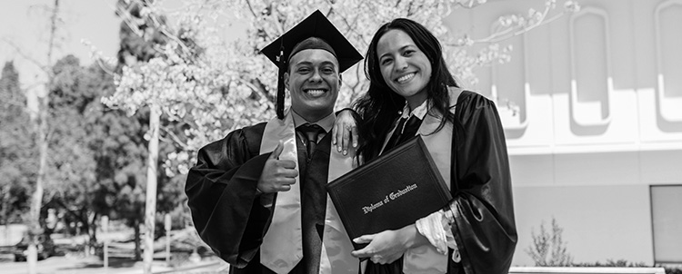 Two graduating people holding diploma